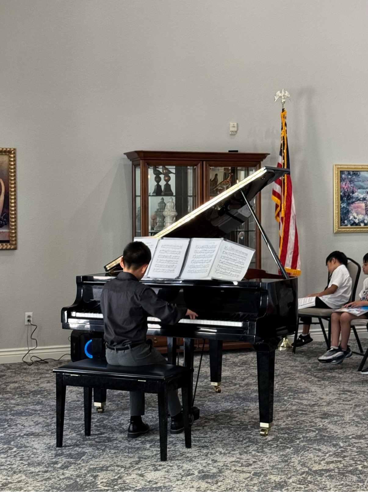A student performing at a piano onstage · 学生在舞台钢琴前演奏